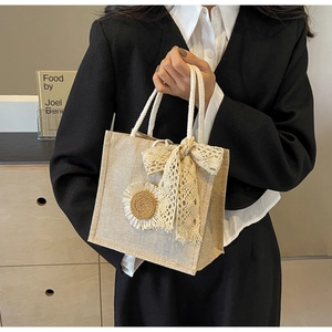 Detail of woven handheld bag with sunflower ornament and white lace bow decoration