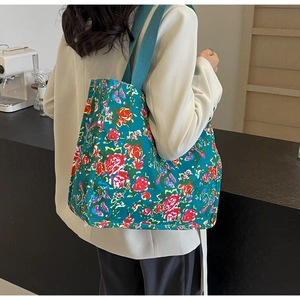 Détail d'un sac cabas en toile verte avec motif rose et large bandoulière tissée