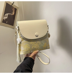 Détail du sac à bandoulière jacquard beige avec broderie de montagne et pompon blanc