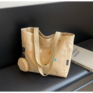 Détail du sac fourre-tout en toile beige avec broderie colorée et mini porte-monnaie