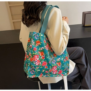 Detail of dark blue floral tote bag with vibrant red and yellow flowers and wide straps