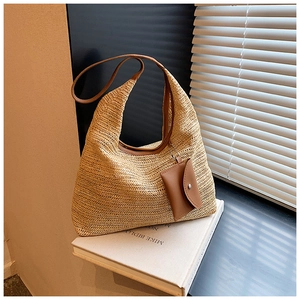 Detail of large woven straw hobo bag showing herringbone texture and leather shoulder strap