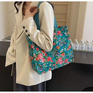 Détail du sac cabas en toile vintage avec imprimé floral rouge sur fond vert et bandoulière
