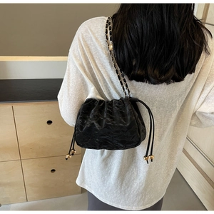 Detail of black pleated cloud crossbody bag featuring drawstring closure and gold metal ball