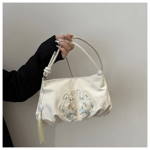 Détail d'un sac à main en soie blanche avec broderie florale et pompon assorti