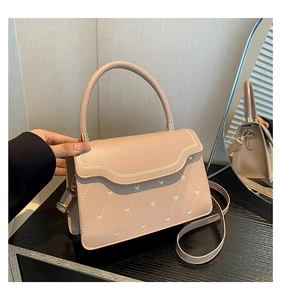 Detail of pink quilted crossbody bag featuring heart embroidery and scalloped edge flap