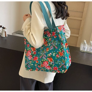 Vue détaillée du sac cabas en toile à fleurs avec larges bandoulières porté par un mannequin