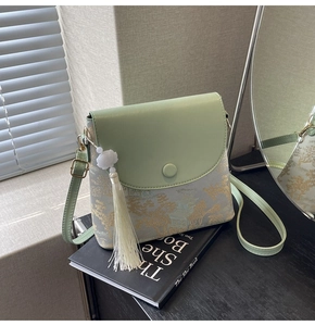 Détail du sac seau bandoulière vert clair avec tissu jacquard et gland blanc