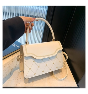 Detail of cream white leather bag with heart quilted embroidery and golden hardware
