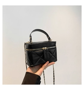 Detail of black quilted leather phone bag featuring gold zipper and metal chain strap