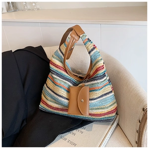 Macro detail of a colorful woven tote bag with a brown leather handle and mini pouch