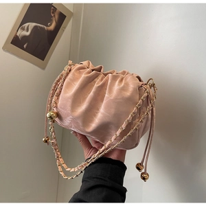 Pink ruched cloud bag with chunky gold chain strap held against a minimalist background