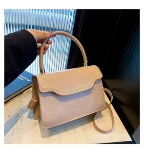 Detail of nude pink handbag featuring heart-shaped quilting and gold chain trim decoration