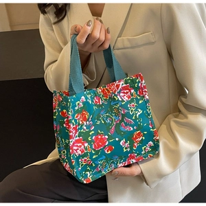 Détail d'un sac cabas en toile à fleurs avec broderie phénix et bouton pression métallique