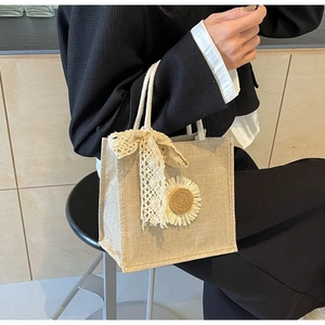 Détail du sac en jute avec nœud en dentelle et tournesol sur fond de bois clair