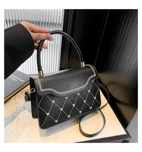 Detail of black leather bag featuring golden wave stitching and heart-shaped metal studs