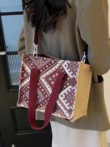 Ethnic woven tote bag with geometric patterns and red handles shown on model