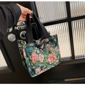 Detail of floral jacquard embroidery and sturdy black handle on mini tote handbag