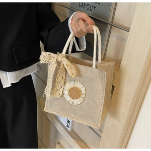 Detail of beige linen tote with crocheted daisies and a lace bow handle decoration