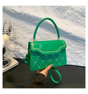 Detail of green crossbody bag with heart rivets, wavy gold zipper edge and quilted stitching