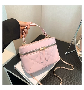Detail of pink quilted handbag with gold zippers and detachable chain strap