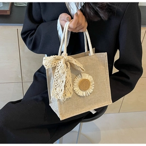 Détail du sac tissé avec broderie tournesol et un délicat nœud en dentelle blanche