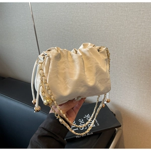 Close-up of white cloud bag with elegant pleated design and gold metal chain strap