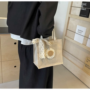 Détail du sac cabas en jute avec nœud en dentelle blanche et applique de tournesol