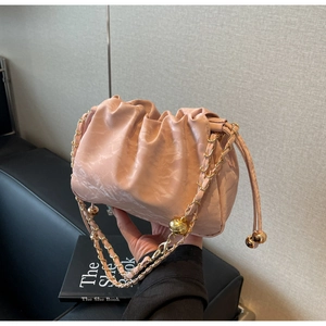 Detailed shot of pink pleated drawstring bag featuring large gold spherical ornaments