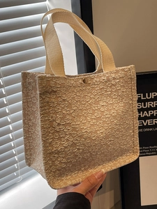 Minimalist beige tote bag with floral jacquard texture and golden snap closure