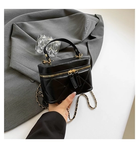 Detail of black quilted leather mini bag with double gold zippers and chain strap