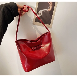 Macro shot of glossy red patent leather bag with bow detail and thin handle