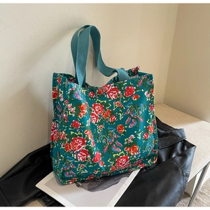 Détail du sac cabas en toile vert foncé avec motif de roses rouges sur une veste en cuir