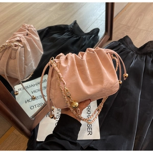 Detailed close-up of pink ruched cloud bag featuring gold chain strap and metal ball
