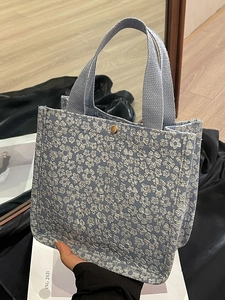 Blue canvas tote bag with 3D floral relief pattern and gold metal clasp closure