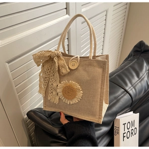 Détail du sac à main tissé beige avec applique marguerite et nœud en dentelle délicat