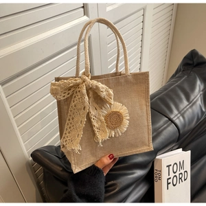 Détail du sac à main en jute avec nœud en dentelle, fleur de tournesol et anse en corde