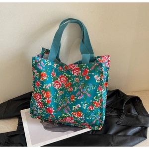 Detailed shot of ethnic floral tote bag on black leather jacket and magazine background
