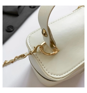 Close-up of white quilted leather bag with gold hardware and woven chain strap detail