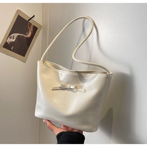 Close-up of a creamy white shoulder bag with an elegant bow detail and smooth PU leather