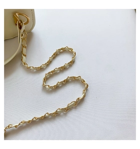 Detail of woven chain strap in gold and cream leather for a quilted crossbody bag