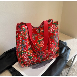 Detail of red floral canvas tote bag with rose patterns and red woven handles