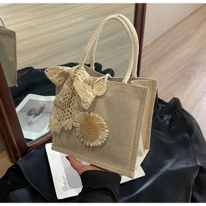 Détail du sac tissé beige orné de marguerites, nœud en dentelle et bouton en bois