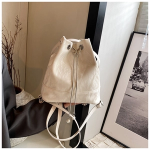 Detail of white patent leather bucket bag with metal butterfly hardware and pearl chain