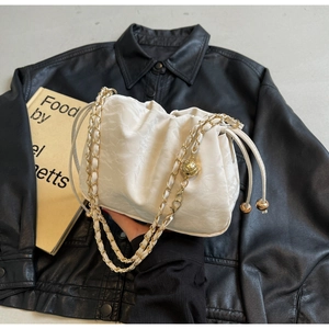 Detail of white cloud drawstring bag with gold chain strap and spherical charm