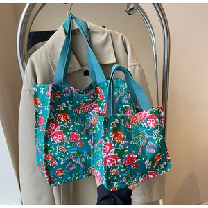 Detail view of large and small floral canvas tote bags with rose prints and woven handles