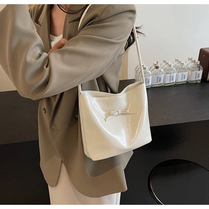 Close-up of white glossy leather shoulder bag with a central bow decoration