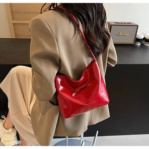 Close-up of a glossy red patent leather underarm bag with a chic bow decoration
