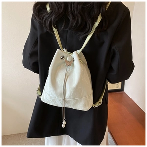 Detail of mint green drawstring backpack with silver butterfly buckle and pearl tassels