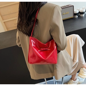 Chic red patent leather handbag with bow detail shown in a stylish urban lifestyle setting